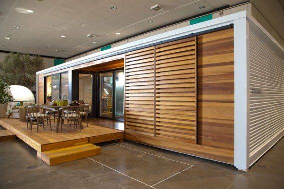 Modern home with wooden deck, sliding wood slat door, and glass walls.
