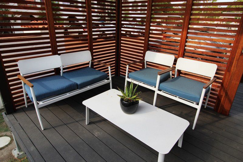 Outdoor seating area with white furniture, blue cushions, and a wooden privacy screen.