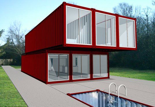 Red container home with glass walls, set on a concrete slab, with a pool.
