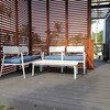 Outdoor white seating area with blue cushions, wooden screen background.