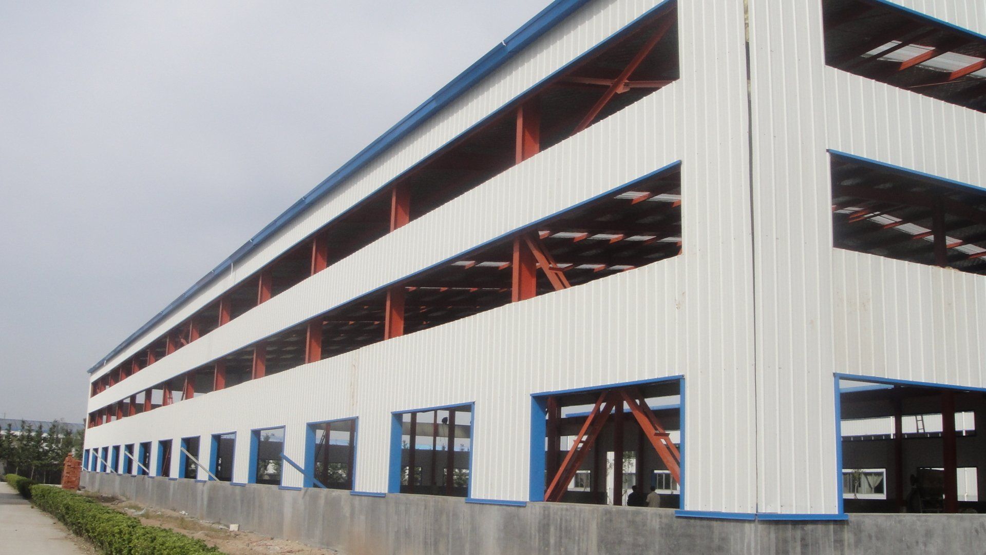 A large, multi-story industrial building under construction with metal siding and exposed steel framework.
