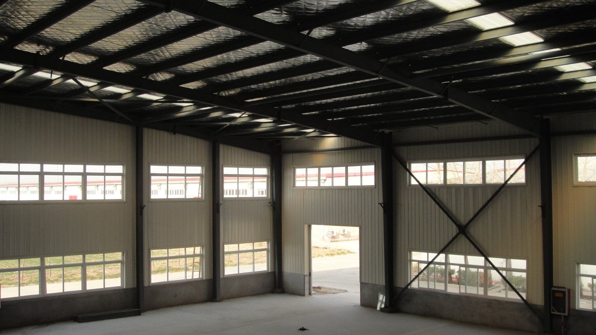 Empty industrial warehouse interior with windows and steel beams.