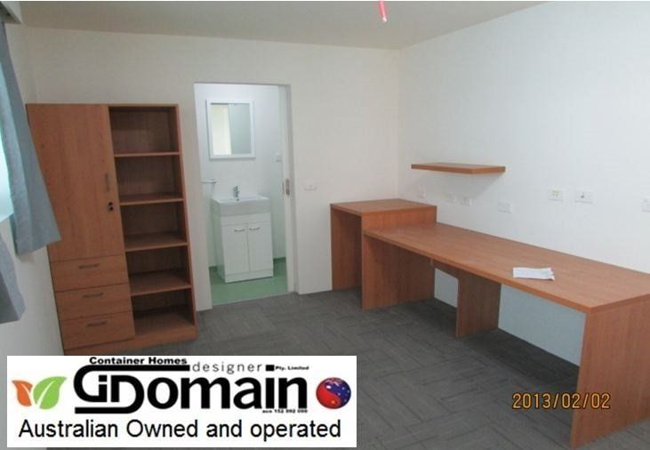 Empty room with a desk, shelves, and a bathroom visible through a doorway. Brown and white furniture.