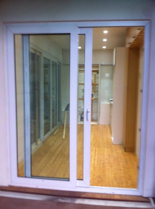 White sliding glass door leading into a brightly lit interior with wood flooring.