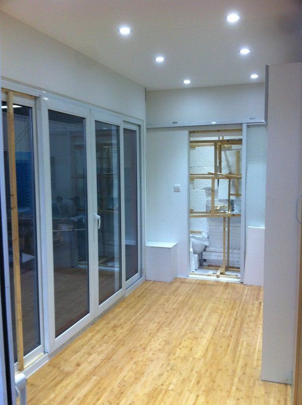 Interior view of a room with folding glass doors, recessed lighting, and bamboo flooring. A built-in display is visible.