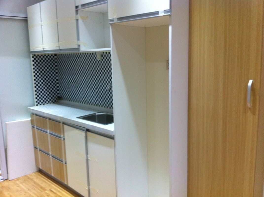Small kitchen with white cabinets, checkered backsplash, and light wood accents.
