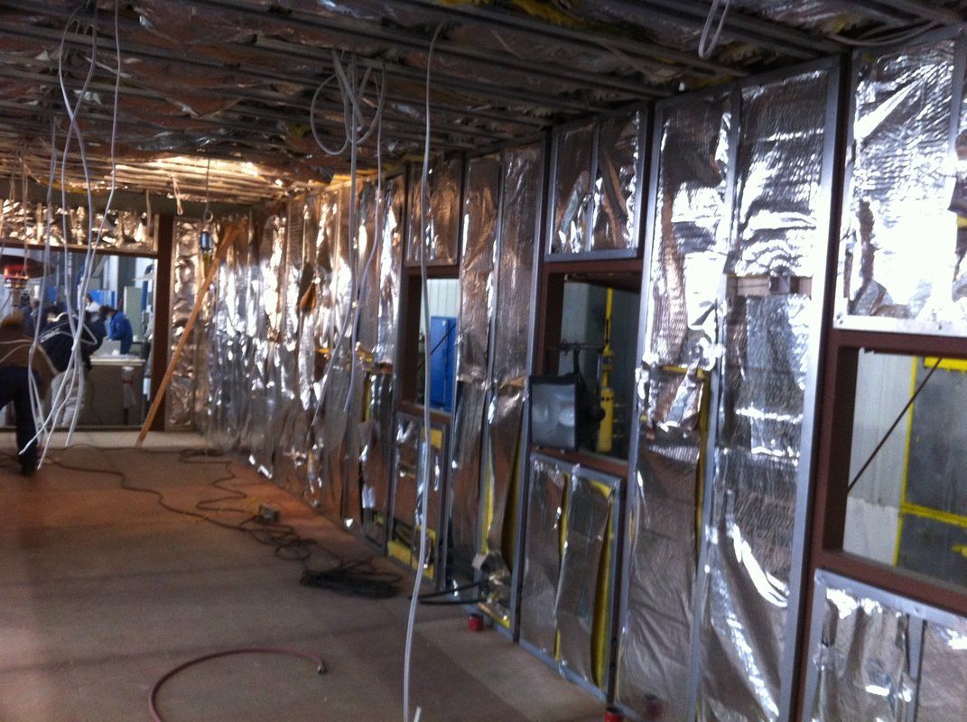 Construction site interior with reflective insulation covering walls and ceiling. Windows are visible.
