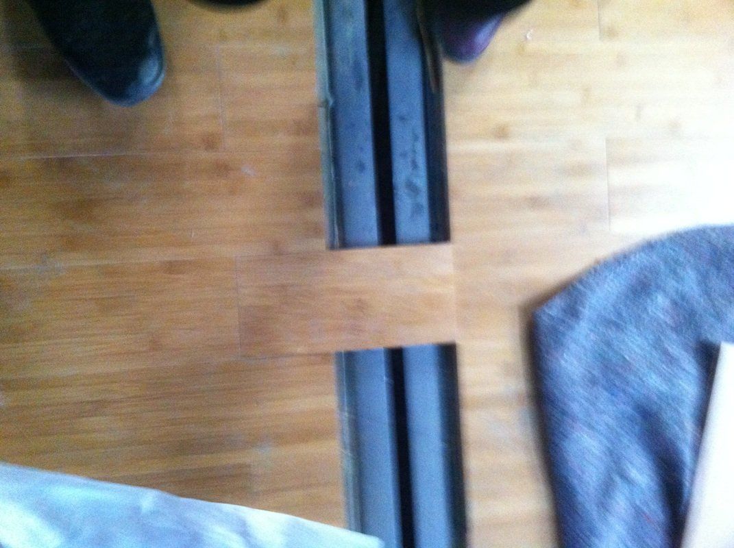 Two rectangular objects with striped patterns separated on a wooden floor, with feet and a cloth partially visible.