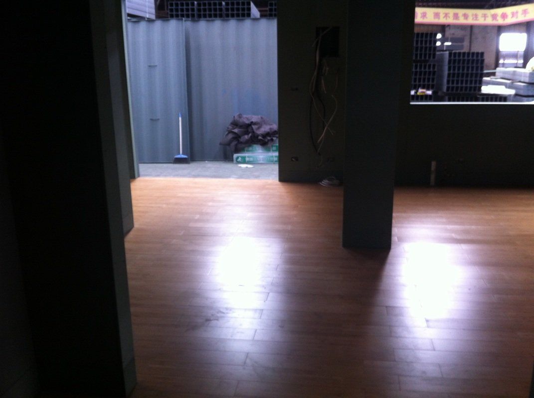 Empty room with hardwood floors, open doorway to an outdoor space. Bright reflections on the floor.