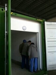 Three people enter a white interior inside a green container.