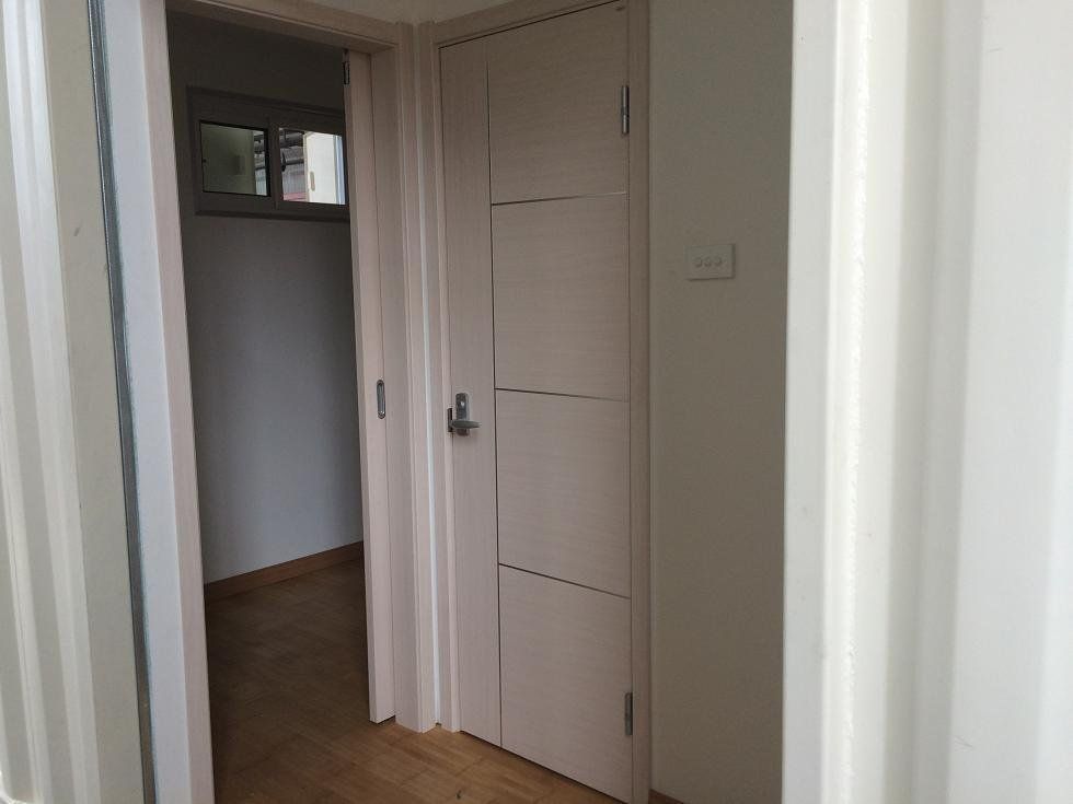 Doorway leading to a corridor with a closed, light-colored door and a small window.
