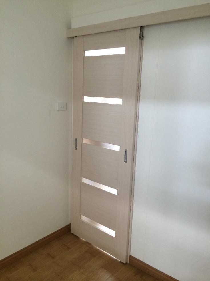 Beige sliding door with four horizontal glass panels, mounted on a track. Corner of a room.