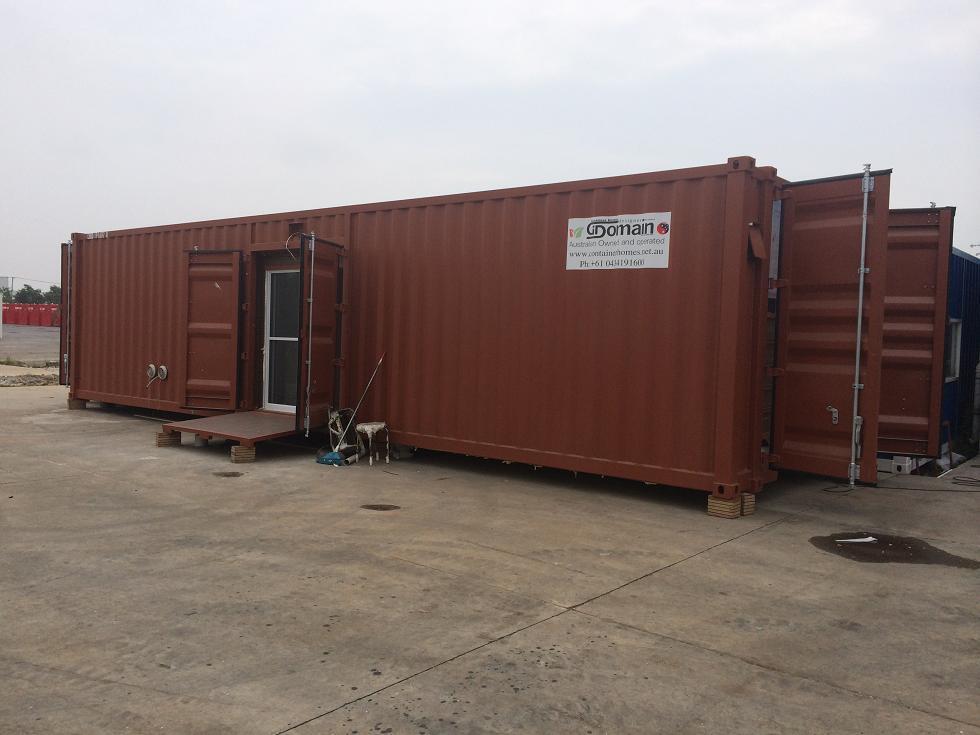 Brown shipping container building with open doors, outdoors.