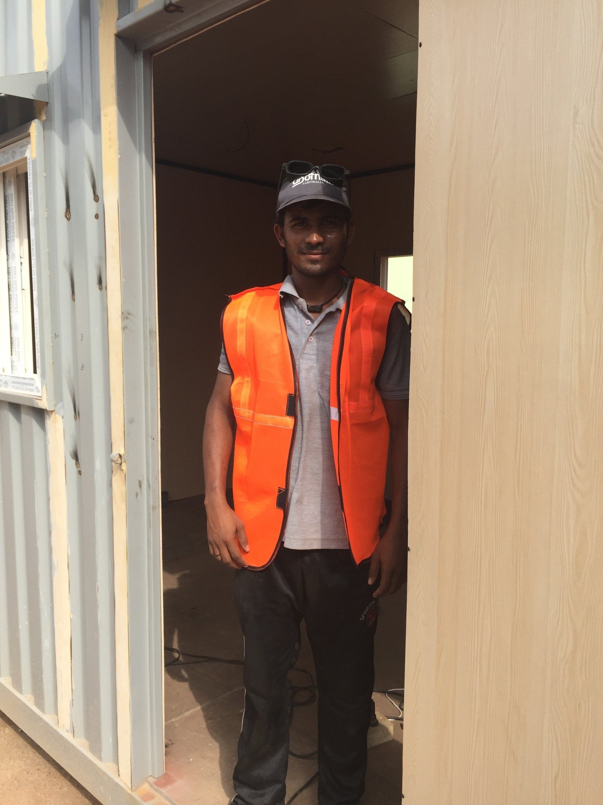 Man in orange safety vest standing in doorway.