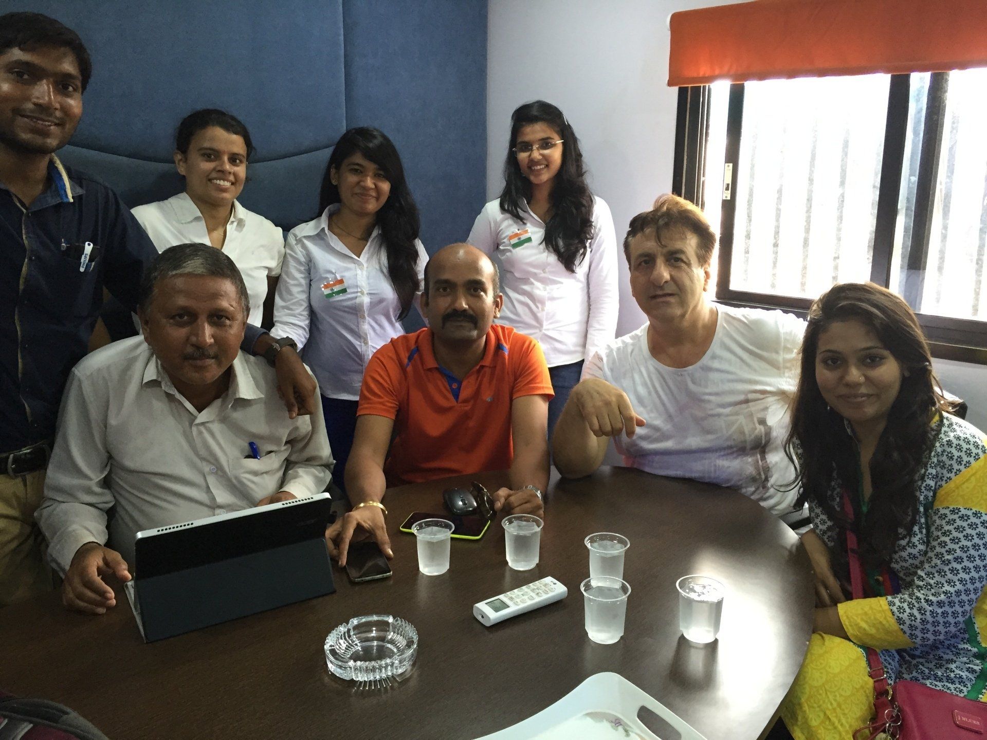 Group of people around a table, some smiling. Indoors, natural light.
