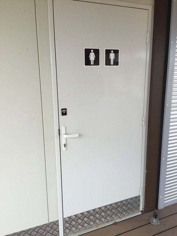 White door with black and white restroom symbols. Metal diamond plate threshold.