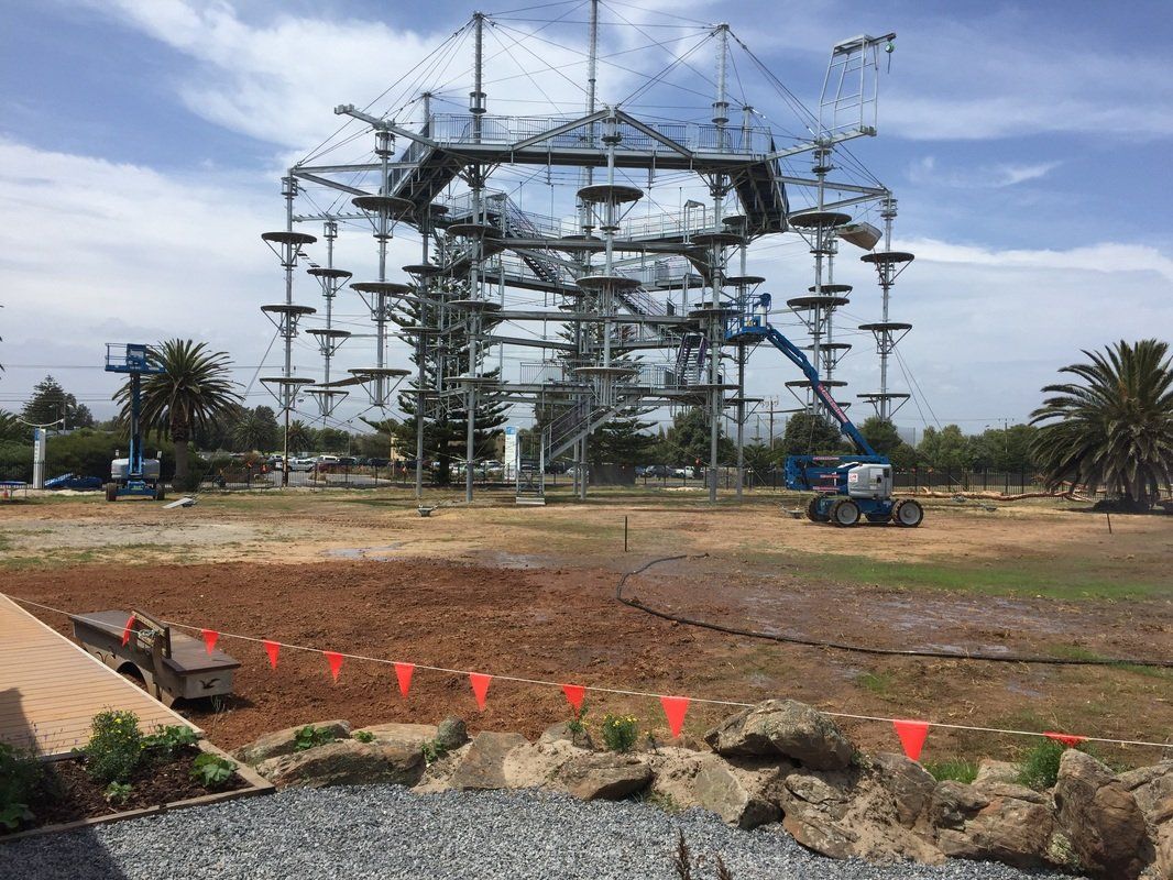 High ropes adventure course with platforms, nets, and bridges, in an outdoor setting.