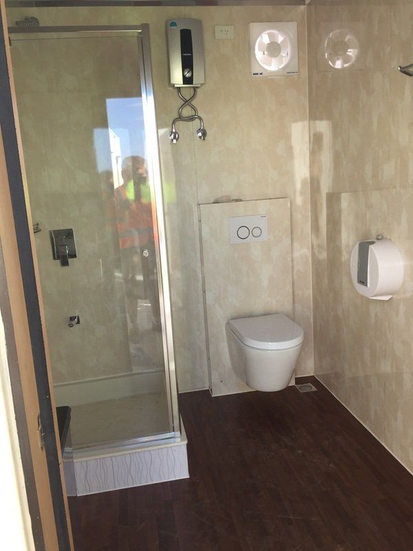 Bathroom with shower, toilet, and sink. Beige walls, dark wood floor.