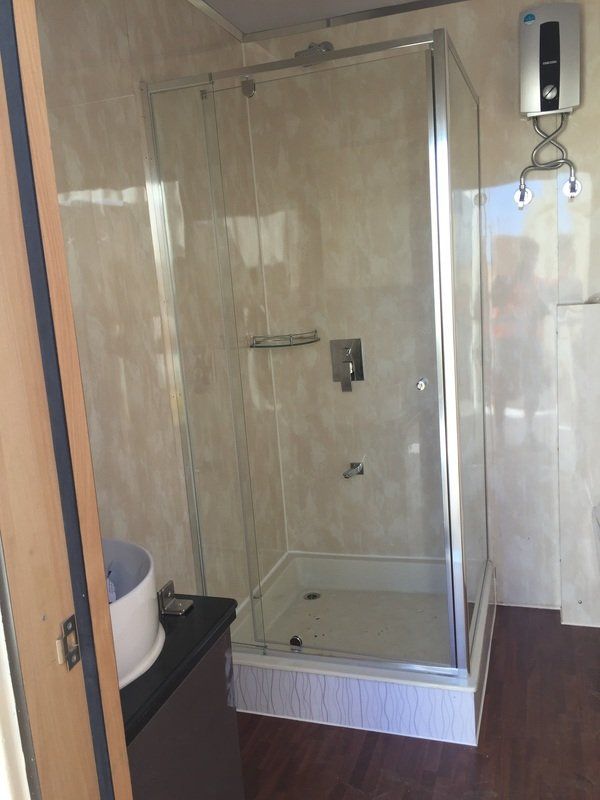 Shower stall with a glass door, in a bathroom with light-colored tile walls.