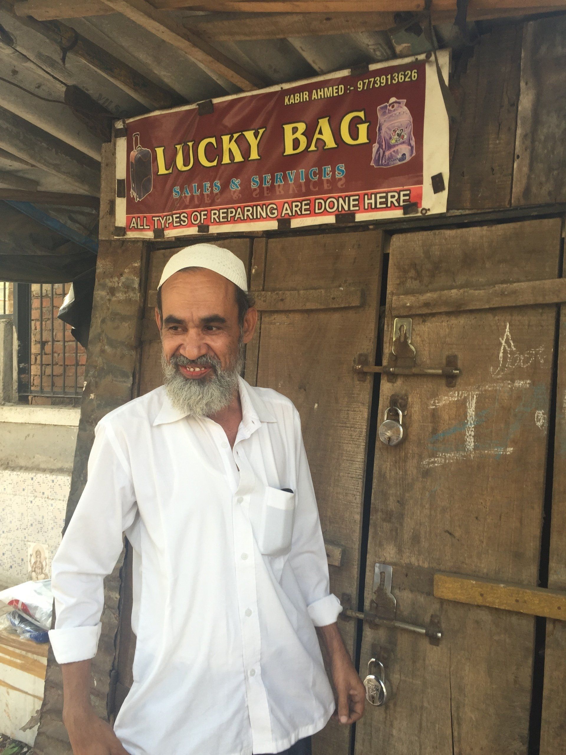 Man in white shirt stands in front of a shop with a