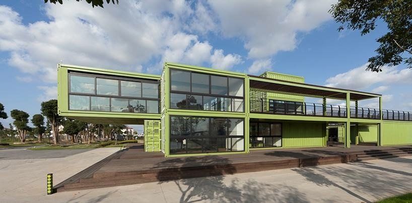 A lime green building constructed of shipping containers with large windows.