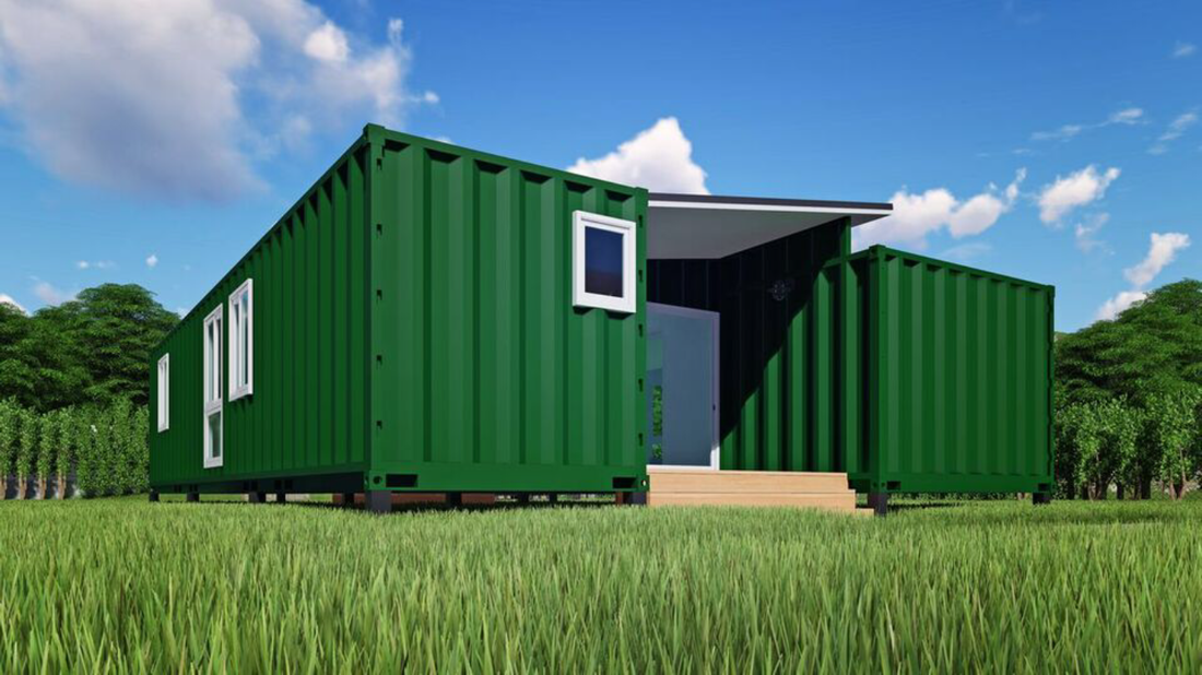 Green container home in a grassy field with a blue sky.