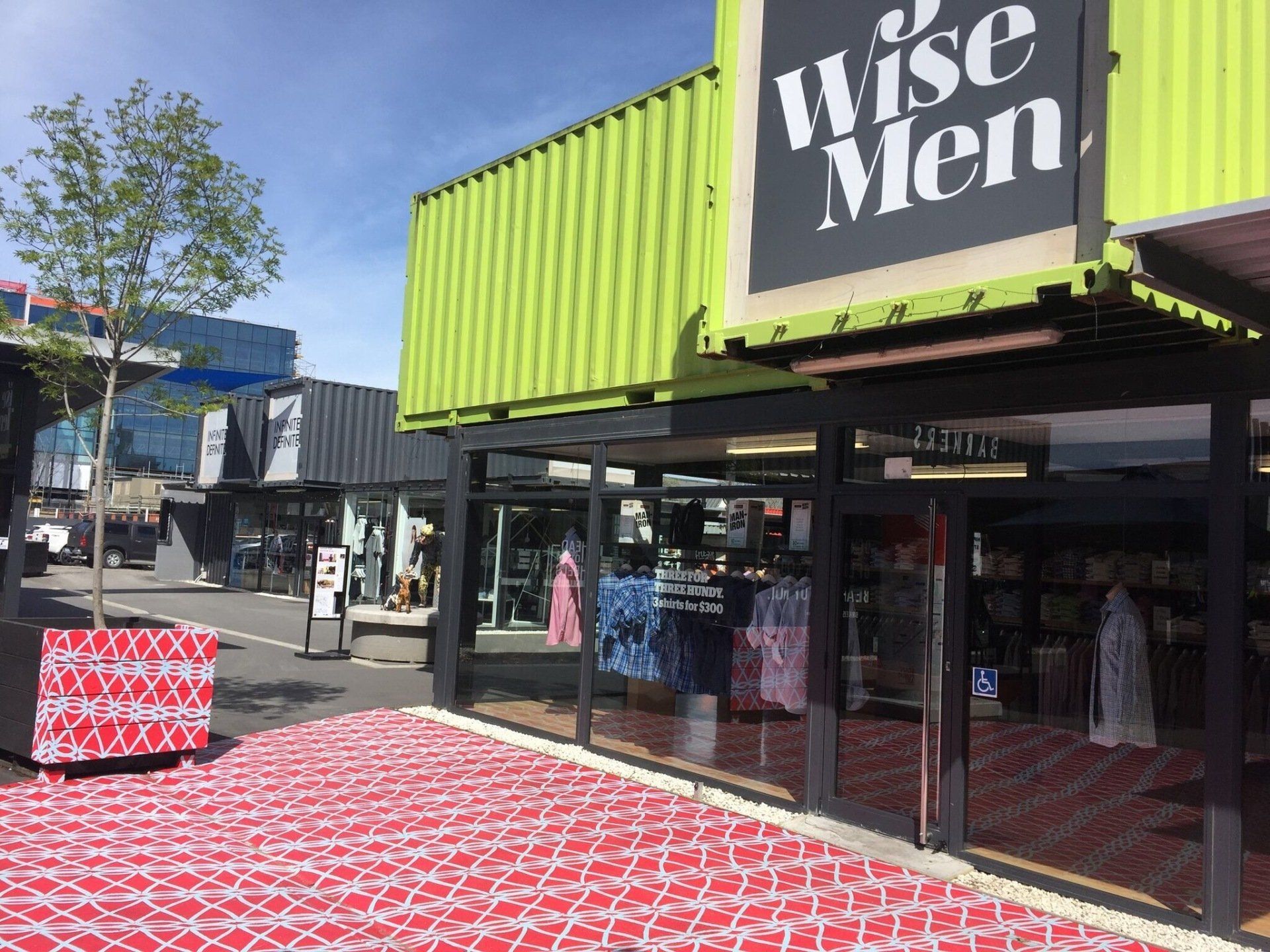 Shops made from shipping containers with a red and white tiled walkway.