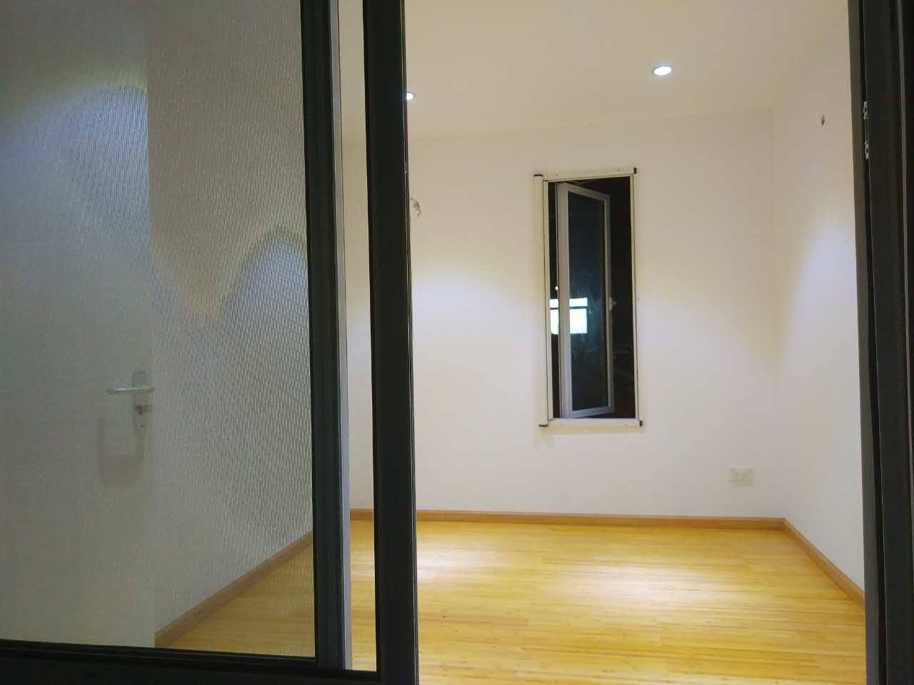 Empty room interior with open window, wooden floor, and white walls.