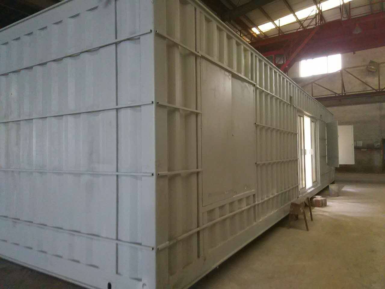 White rectangular building made from shipping containers with a small window and door.