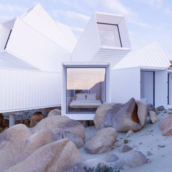 White modern house built amongst large rocks, with geometric shapes and angular windows.