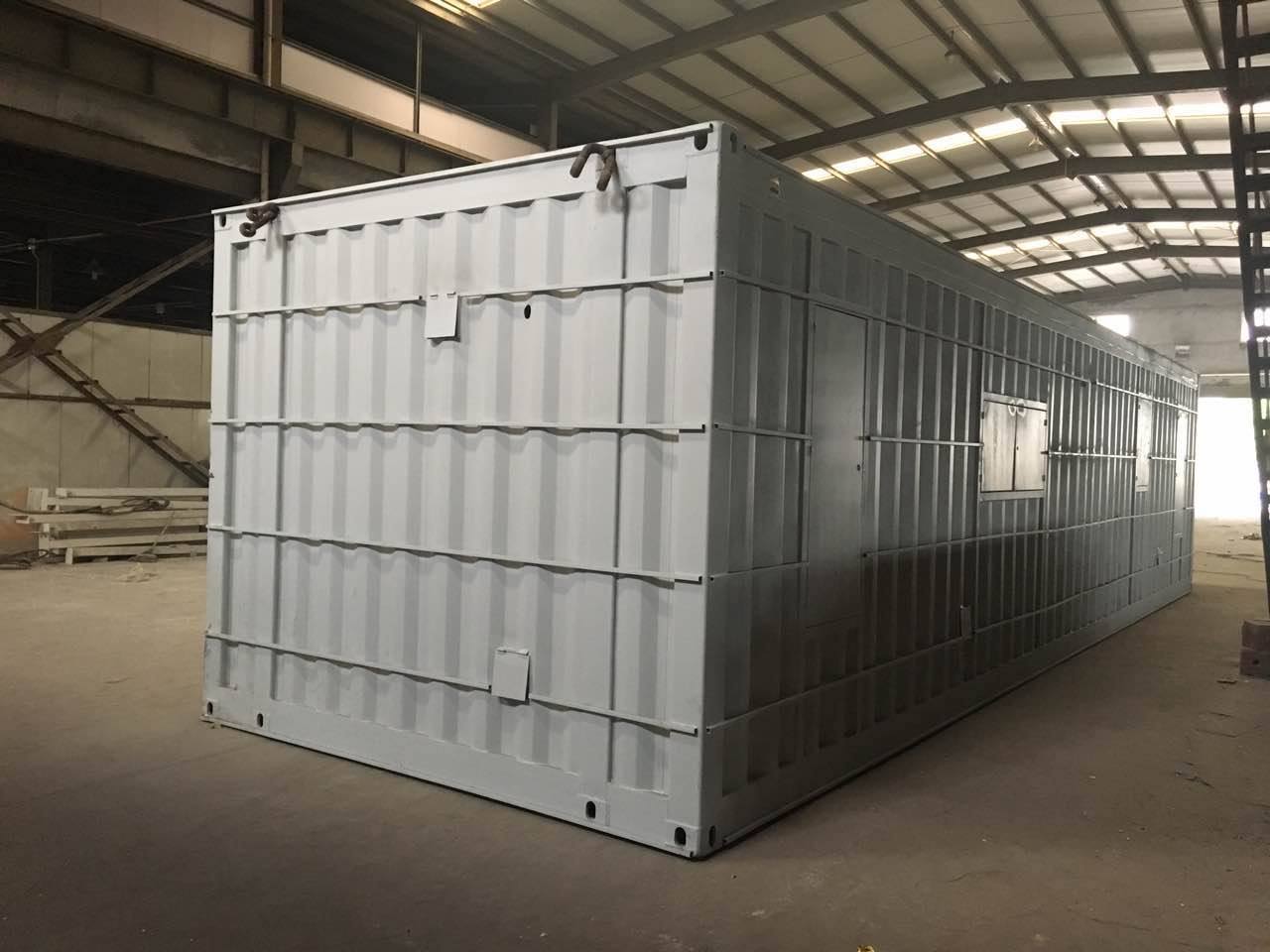 Gray shipping container with small windows, indoors.