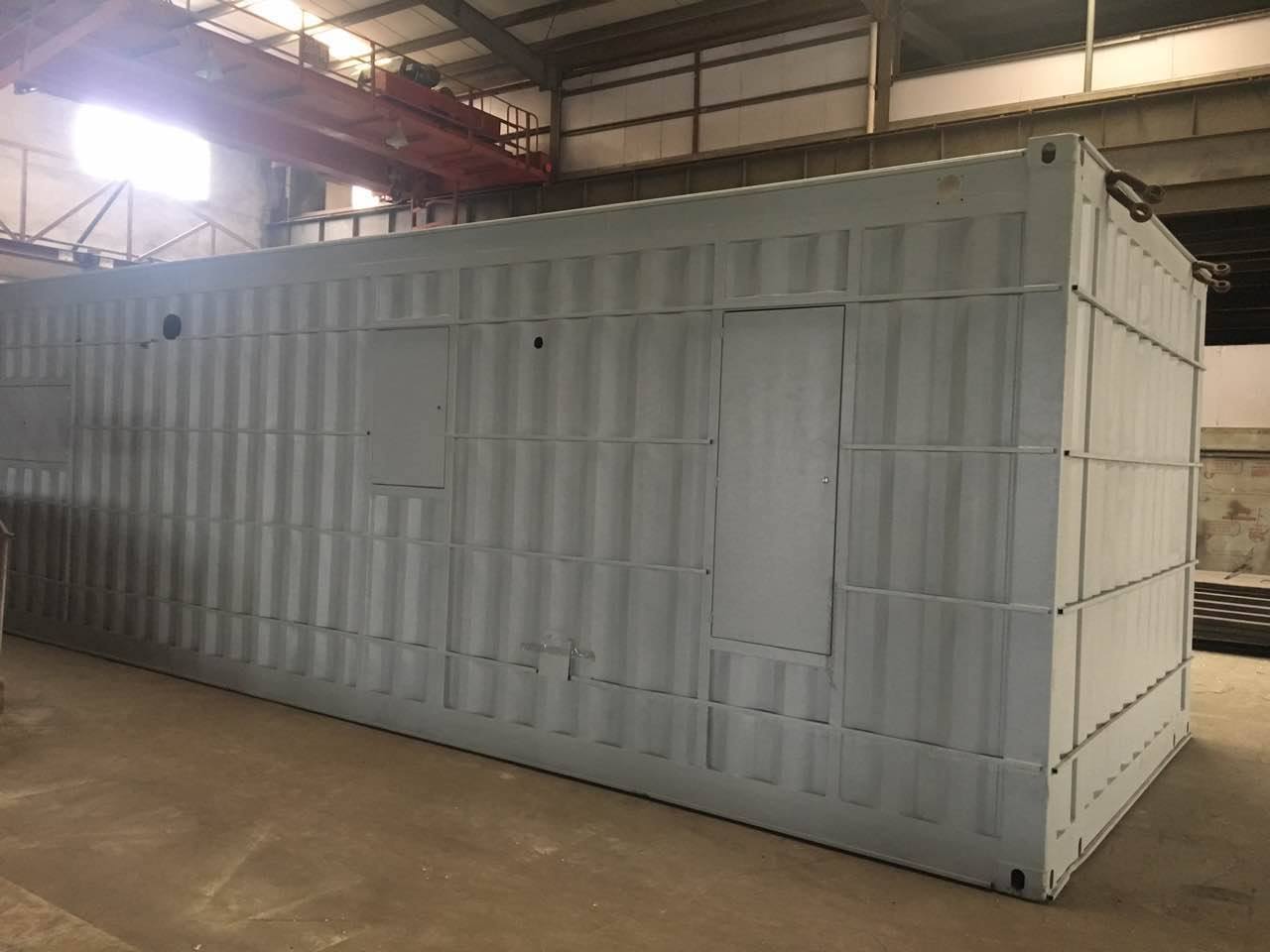 Large gray metal shipping container with two rectangular openings, inside a warehouse.