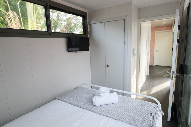 Small bedroom with a bed, TV, closet, and open doorway to hallway.
