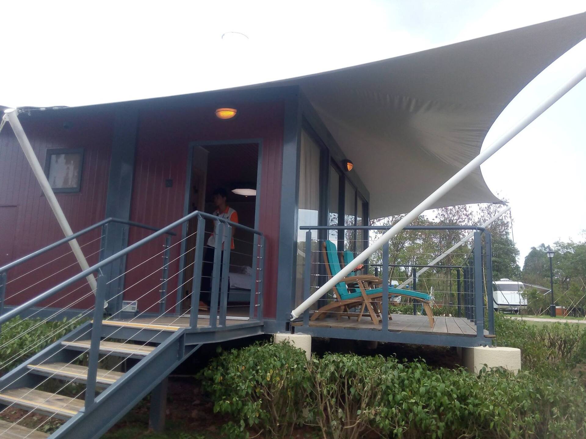 Cabin with steps, deck, and awning. A person stands in the doorway.