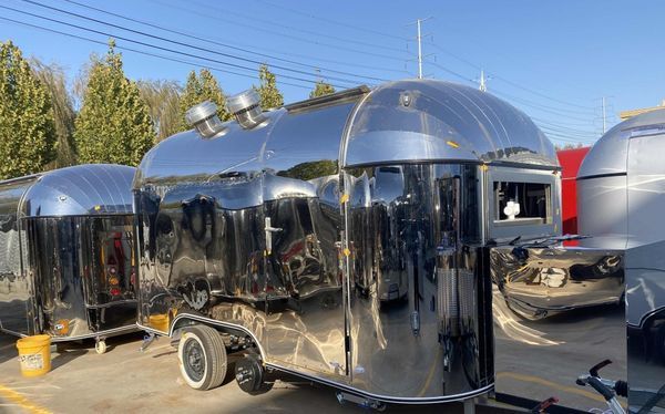 Shiny, silver trailer with rounded top and exhaust vents. Parked outside.