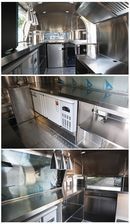 Interior of a stainless steel food truck kitchen, featuring counters, refrigeration, and ventilation hood.