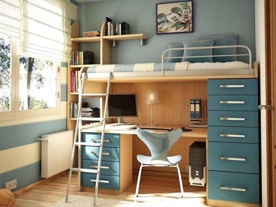 Loft bed with desk and drawers in a blue and wood-toned room. Bookshelves, window with blinds.