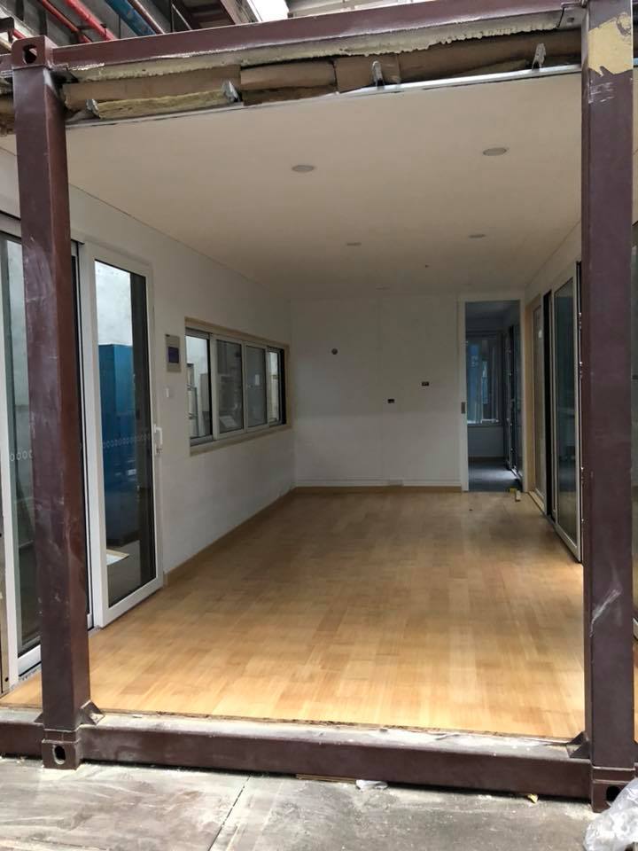 Interior of a container home with wood floors, white walls, and glass doors and windows.