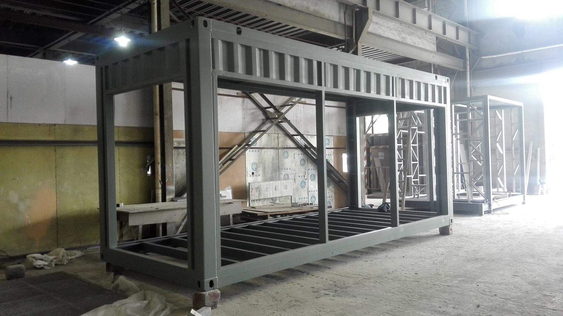Steel framework of a container in a workshop. Gray metal structure, open sides, with a grid floor.