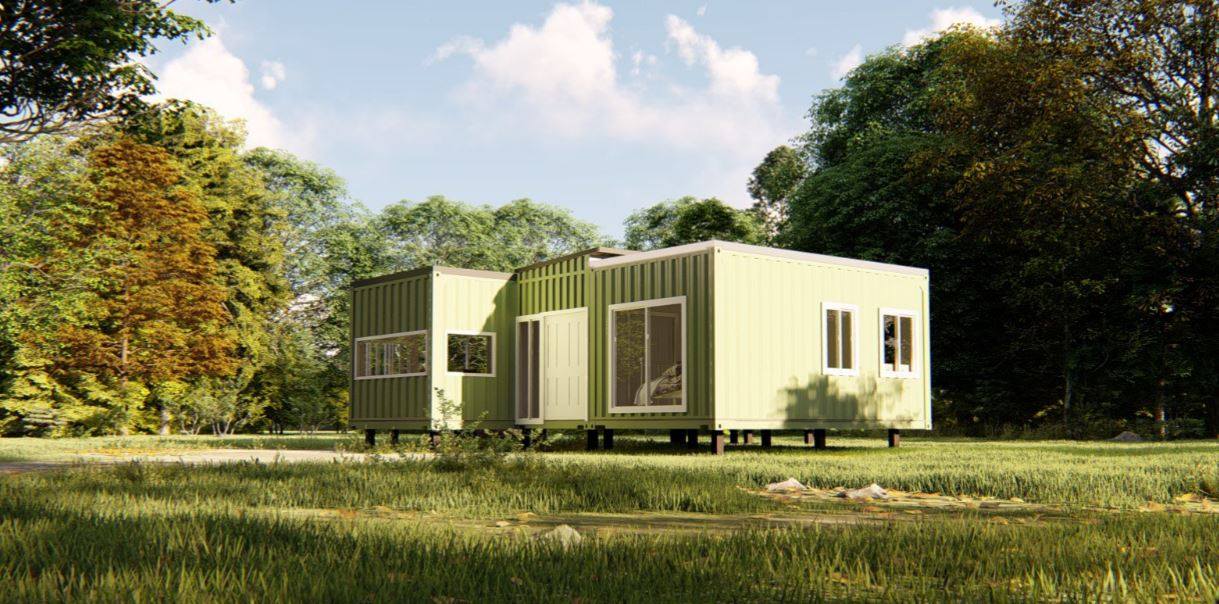 A light green modern home built from shipping containers sits in a grassy field, surrounded by trees.