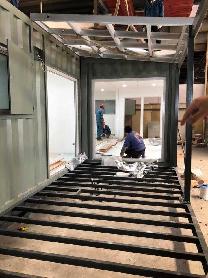 Construction of a building: Workers inside a container, framing and flooring.