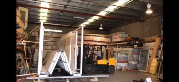 A forklift carrying building materials inside a warehouse.