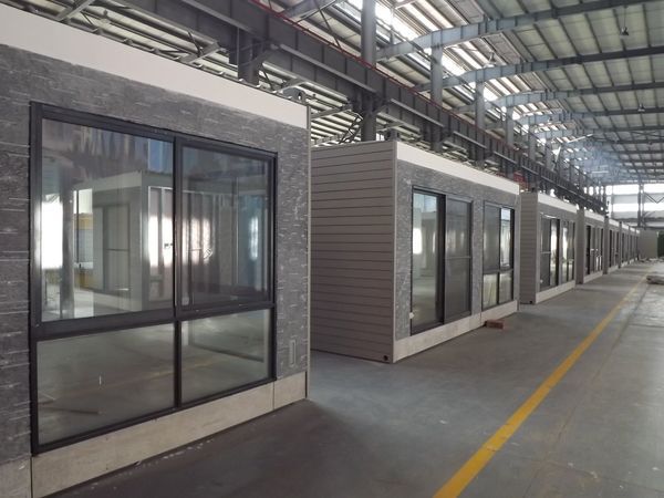 Several modular buildings with large windows inside a factory.