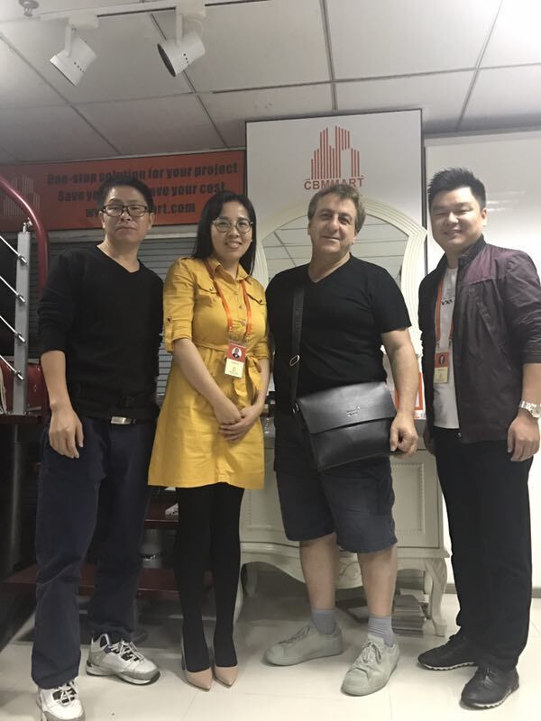 Four people posing in front of a cabinet, inside a store. One wears a yellow dress.