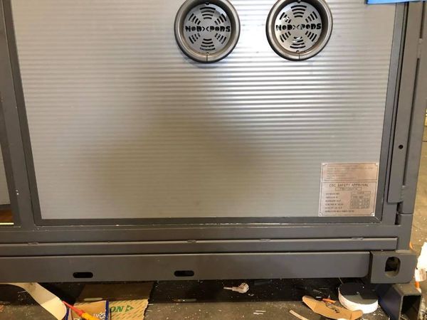 Gray metal cabinet with two circular vents, a glass panel, and a rectangular base.