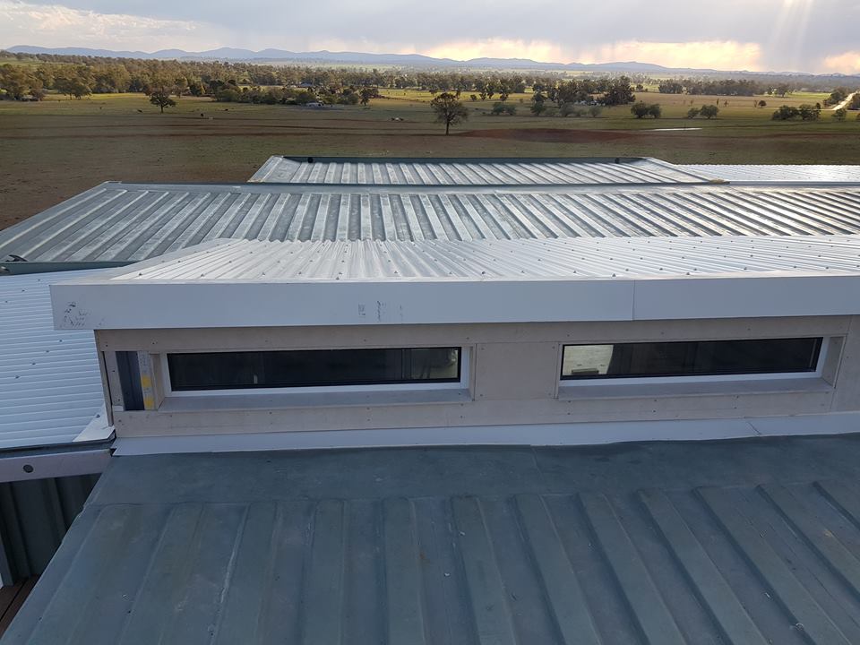 View from a roof with metal panels, windows, and a vast, grassy landscape.