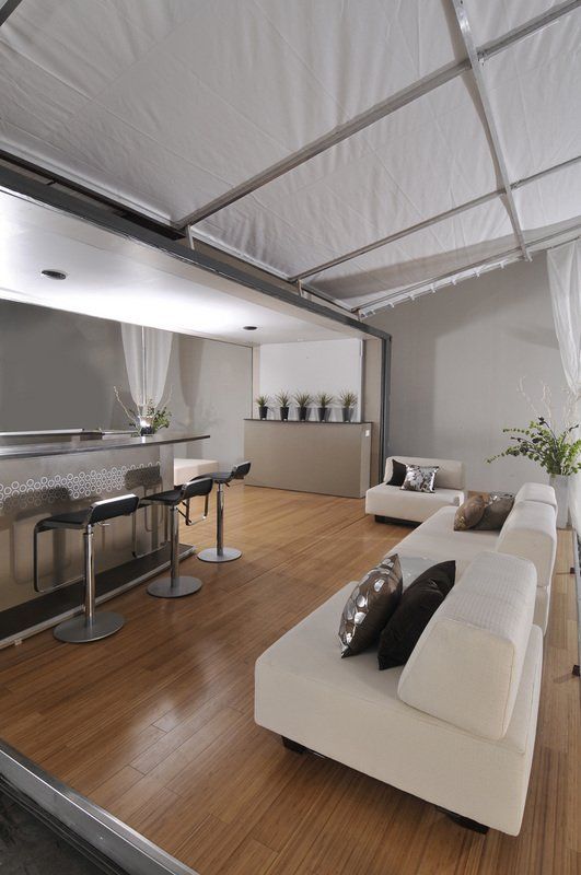 Modern lounge with white sofas, bar seating, wood floor, and sheer white curtains.