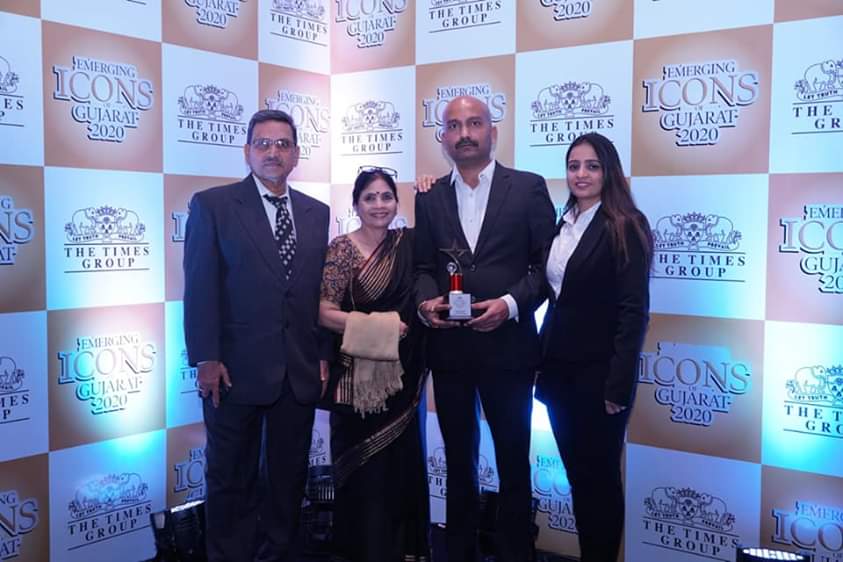 Four people pose at an awards event with a trophy. Event backdrop says