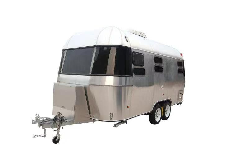 Shiny silver Airstream travel trailer with tinted windows, parked on white.
