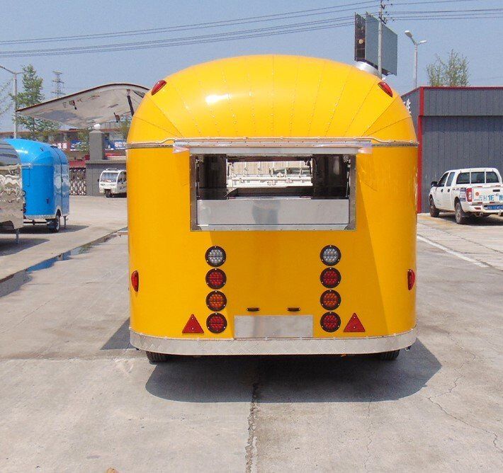 Yellow food truck, rear view, open service window, multiple lights, outdoor setting.